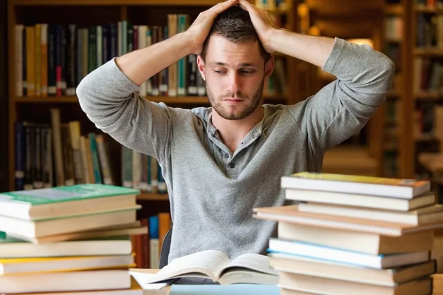 A man browsing books in a library, unsure which one to choose